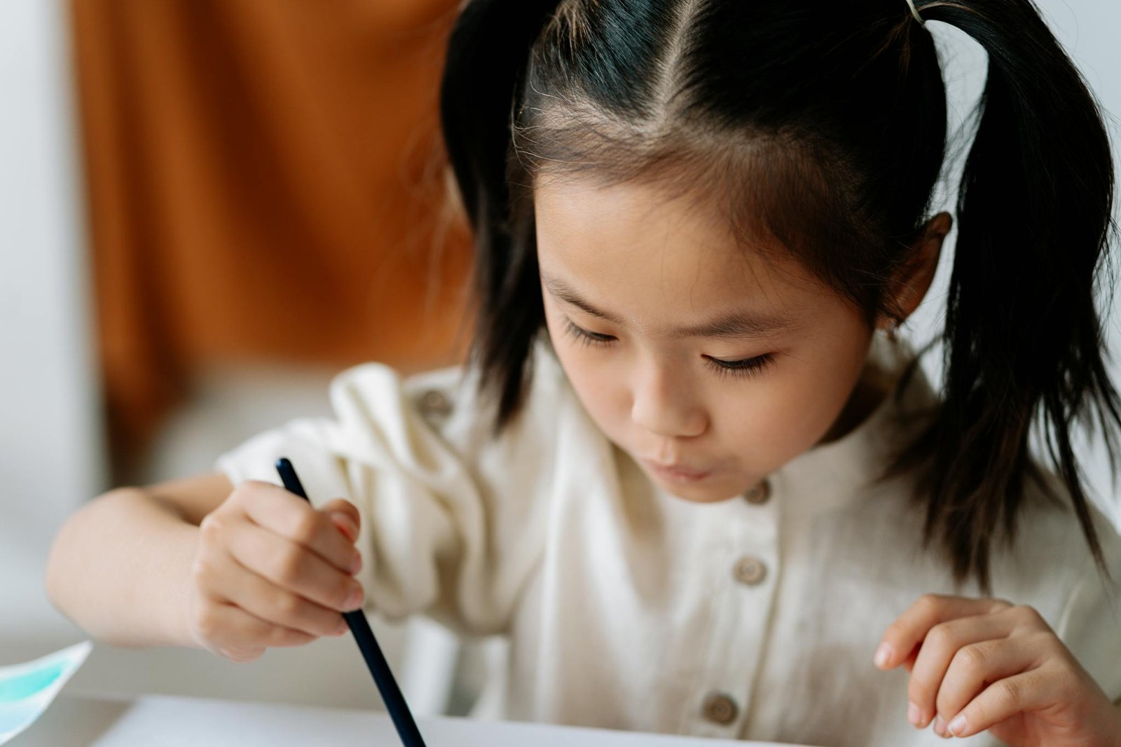 A young Asian child intently painting in an art workshop, showcasing creativity and focus.