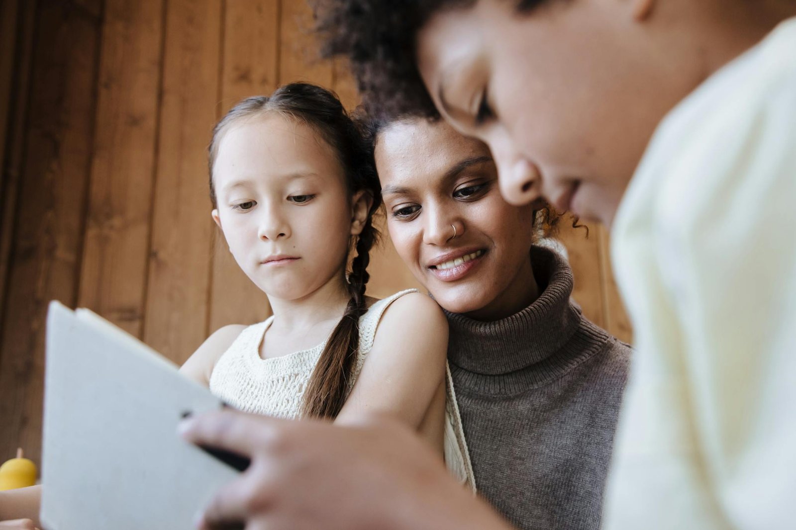 Mother and children bonding over a tablet at home, fostering learning and connection.